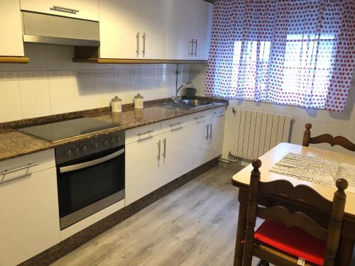 a kitchen with white cabinets and a sink and a table at Piso con vistas Fisterra in Fisterra