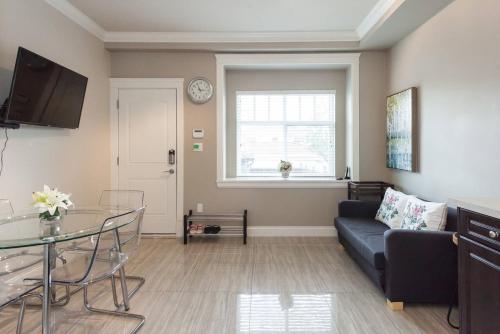 a living room with a couch and a glass table at Rare Find Exquisitely New Quiet & Safe Skytrain Home in Vancouver