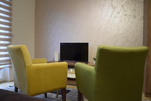 a living room with two chairs and a table with a television at Apartmani Marić in Novi Pazar
