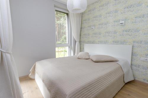 sypialnia z białym łóżkiem i oknem w obiekcie AMI Vanagupės forest w Połądze