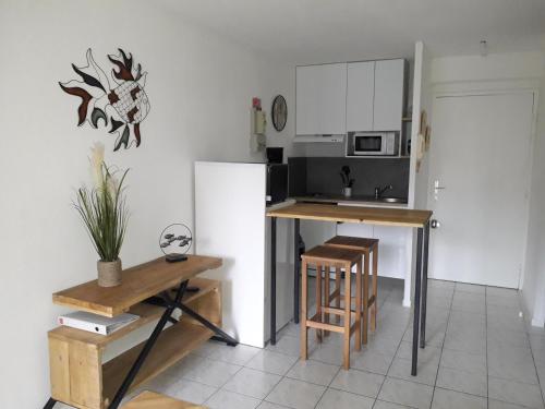Il comprend une cuisine équipée d'un réfrigérateur, d'une table et de chaises. dans l'établissement Le Vénizio - Classé 2 étoiles - T2 climatisé, avec terrasse, parking, prêt de vélos, 10 minutes à pied gare et centre ville, à Sète