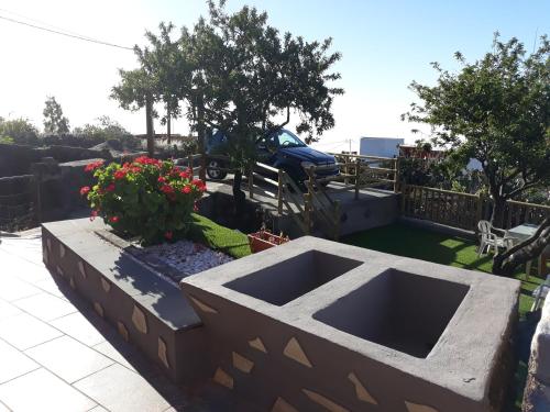 a garden with flowers and a car in a yard at Casa rural meridiano in El Pinar del Hierro