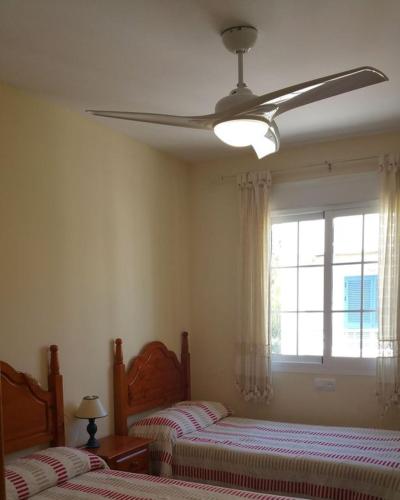 a bedroom with two beds and a ceiling fan at Casa El Algarrobico in Agua Amarga
