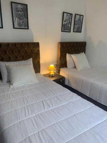 una camera da letto con due letti e un tavolo con una lampada di appartement Lalla ghita essaouira a Essaouira