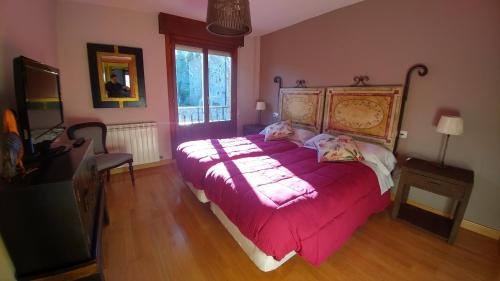 a bedroom with a large bed with a pink comforter at El Mirador de Molinos in Molinos de Duero