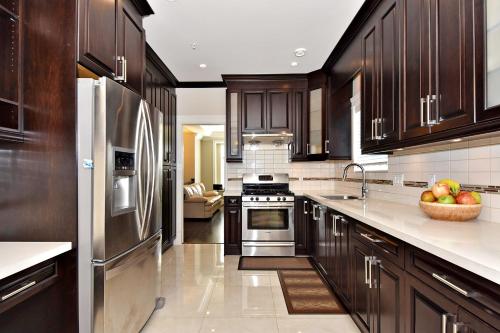 a kitchen with dark wood cabinets and stainless steel appliances at Rare Find Exquisitely New Quiet & Safe Skytrain Home in Vancouver