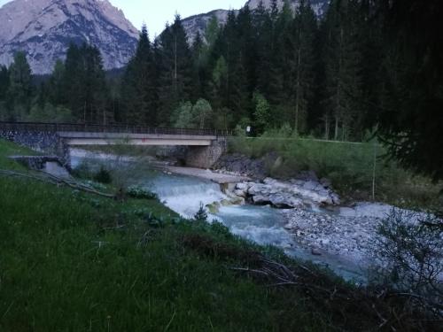 a bridge over a river with a mountain in the background at Plodn House in Sappada