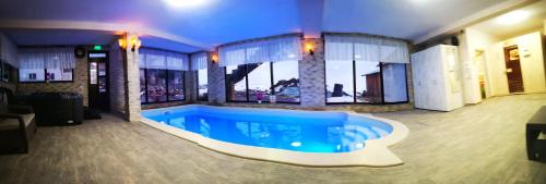 a large swimming pool in a building with a large window at Pensiunea Select Moeciu in Moieciu de Sus