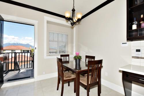 a dining room with a table and chairs and a balcony at Rare Find Exquisitely New Quiet & Safe Skytrain Home in Vancouver