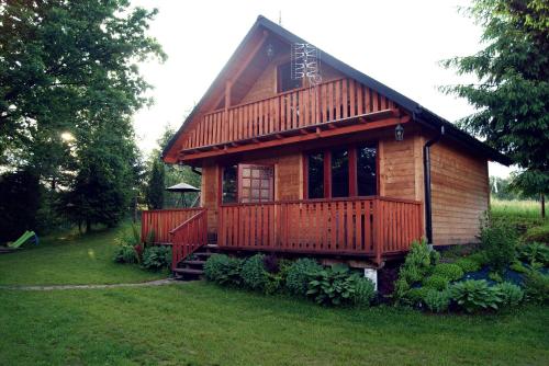 une petite cabane en bois avec une terrasse couverte sur une pelouse dans l'établissement Chrząszczewo Widokowe wzgórze 2, à Uherce Mineralne