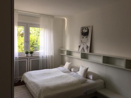 a white bedroom with a bed and a window at Messewohnung Düsseldorf in Düsseldorf