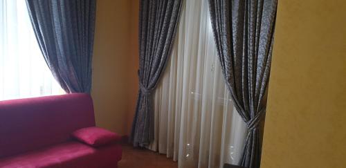 a red couch sitting next to a window with curtains at La Breccia A Porta Pia in Rome