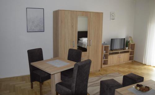 a living room with a table and chairs and a television at Apartmani Marić in Novi Pazar