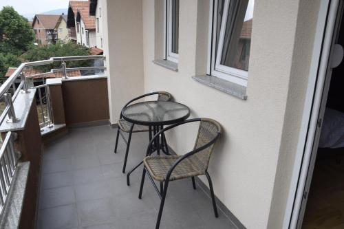 a small table and two chairs on a balcony at Apartmani Marić in Novi Pazar