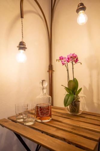 a wooden table with a bottle of whiskey and a vase of flowers at Casa Vacanze Gombito 4 Bergamo Alta in Bergamo