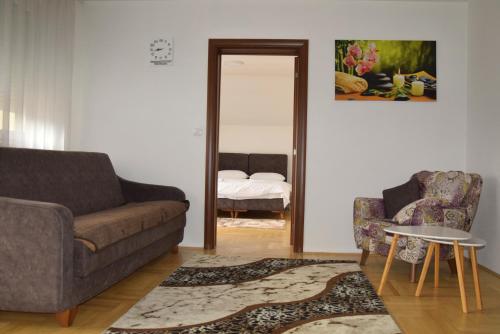 a living room with a couch and a chair and a mirror at Apartmani Marić in Novi Pazar