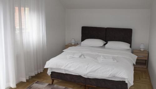 a bedroom with a large bed with white sheets at Apartmani Marić in Novi Pazar