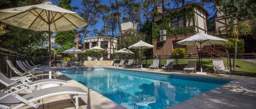 uma piscina com cadeiras e guarda-sóis ao lado de uma casa em Puerto Hamlet em Carilo