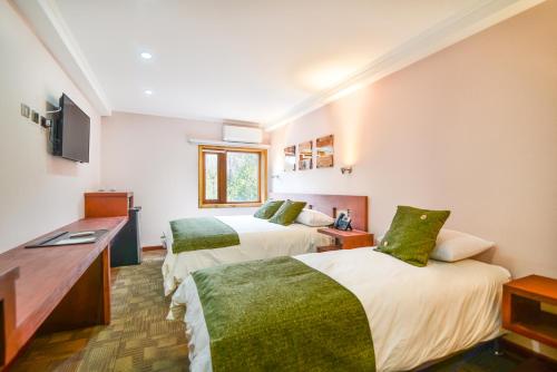 Una habitación de hotel con dos camas y un escritorio. en Hotel Pucón Indómito, en Pucón