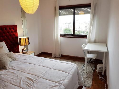 a bedroom with a bed and a desk and a window at Oporto Cozy Rooms in Porto