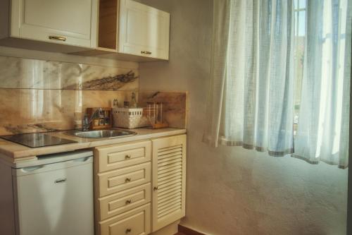 a kitchen with white cabinets and a sink and a window at Moonshine Guest House with private studios and private cottage in Lagos