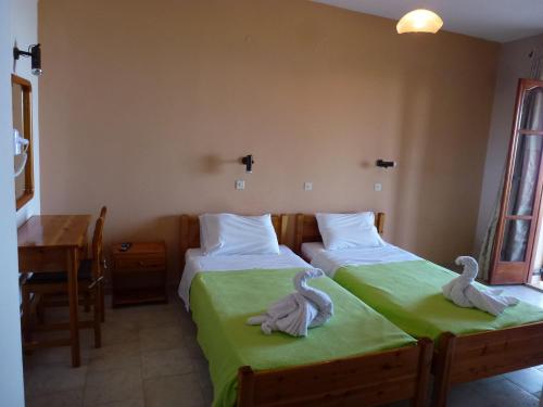 two beds in a room with swans towels on them at Marinos Studios at Lourdata village in Lourdhata