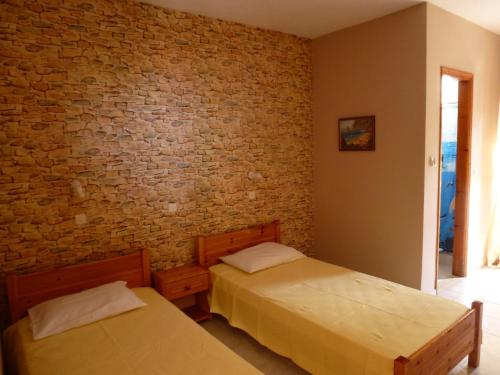 two beds in a room with a brick wall at Marinos Studios at Lourdata village in Lourdhata