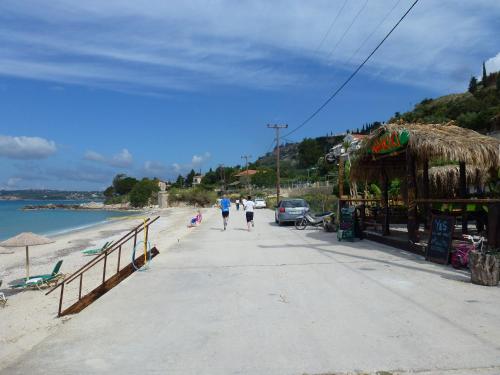 a couple of people walking down a sidewalk on the beach at Marinos Studios at Lourdata village in Lourdhata