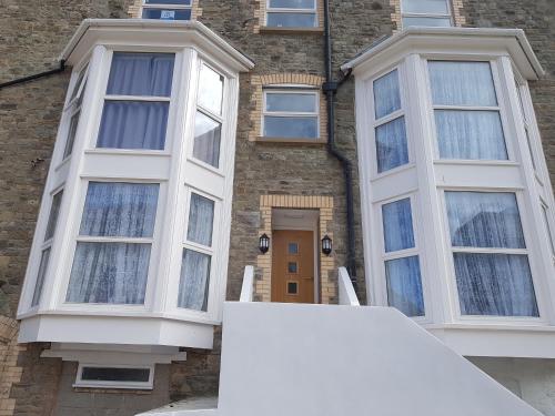 een huis met witte ramen ervoor bij Runnacleave Court, apartment 2 in Ilfracombe