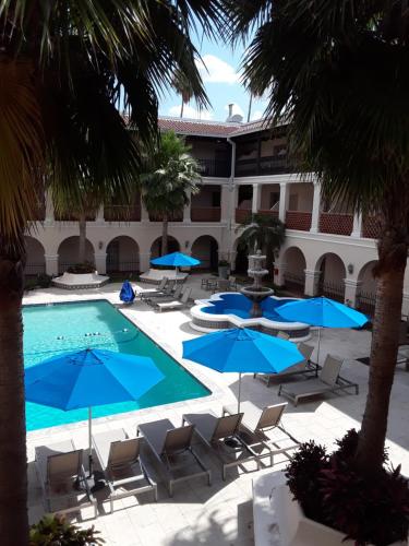a courtyard with chairs and a swimming pool with blue umbrellas at Casa De Palmas, Trademark Collection by Wyndham in McAllen