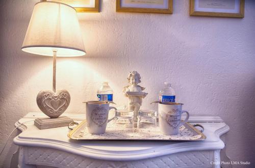 a table with a lamp and a statue of a girl on it at Maison d'hôtes de charme La Rose de Ducey près du Mont Saint Michel in Ducey