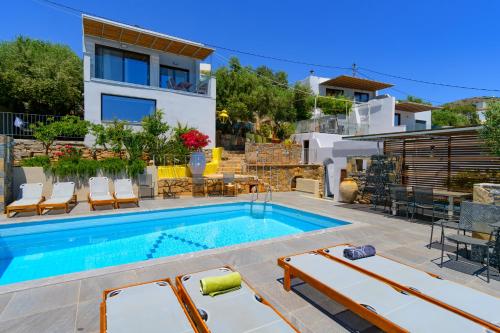 a swimming pool with chairs and a house at Villa Olga in Agios Nikolaos