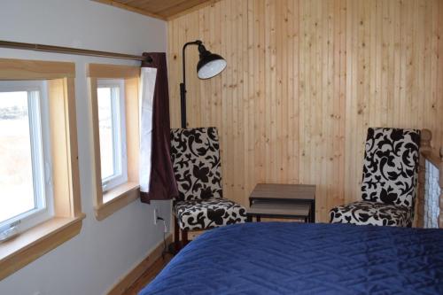 una camera da letto con due sedie e un letto e finestre di Bird Island Accommodations Elliston a Elliston