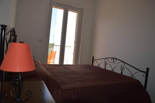 a bedroom with a bed with a lamp and a window at 21mq Home Petrolla in Villanova di Ostuni