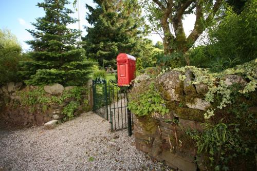 a red phone booth sitting next to a stone fence at The Rock Inn in Bovey Tracey