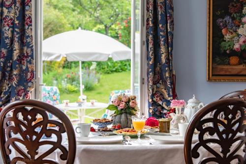 a table with food and drinks on a table with chairs at Maison d'hôtes de charme La Rose de Ducey près du Mont Saint Michel in Ducey