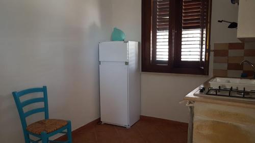 eine Küche mit einem weißen Kühlschrank und einem blauen Stuhl in der Unterkunft Casa Paola in Favignana