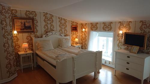 a bedroom with a white bed and a television at Garvaregården Hotel , B&B och Café in Askersund