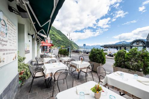 a restaurant patio with tables and chairs and a street at Hotel Argegno in Argegno