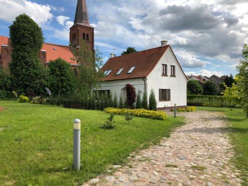 a white house with a church in the background at Willa Basztowa 5 in Pasym