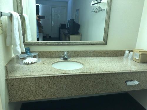 W łazience znajduje się umywalka i lustro. w obiekcie Delta Inn w mieście West Helena