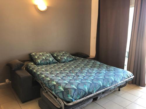 a bed with a blue comforter in a bedroom at Porticcio centre plage à pieds, studio-cabine 4 Pers max, promo 7 nuits in Porticcio