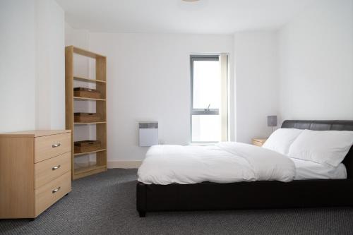 a bedroom with a large bed and a dresser at Serviced Apartment In Liverpool City Centre - Free Parking - Balcony - by Happy Days in Liverpool