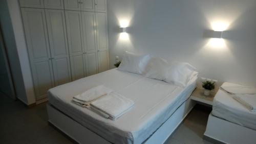 a white bed with two towels and two lights on it at Niso in Livadion