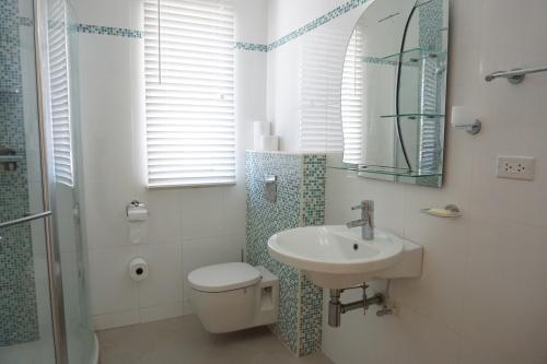 Un baño con lavabo, inodoro y espejo. en High-End finished apartment Higher Heights, Barbados, en Christ Church