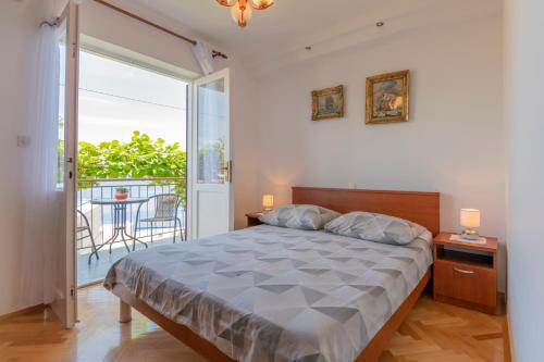 a bedroom with a large bed and a balcony at Apartments Amalia in Podgora