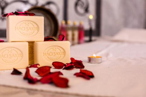 a table with three candles and red rose petals at Thermal Saray Hotel & Yalova in Gokcedere