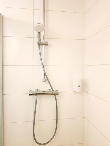 a shower in a bathroom with white tiles at Aparthotel Pan Haus in Bad Ischl