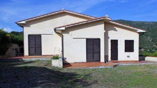 mały biały dom z czarnymi okiennicami w obiekcie Capoliveri Punta Morcone bilo w mieście Capoliveri