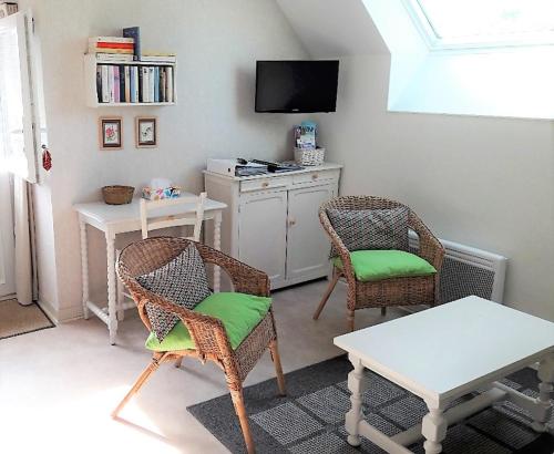 ein Wohnzimmer mit zwei Stühlen und einem Tisch und einem Fernseher in der Unterkunft LA BIGOTTIERE DU PORT in Saint-Georges-sur-Cher